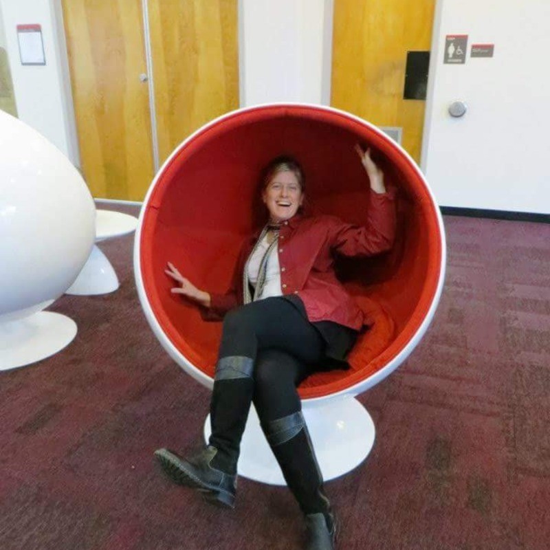 A photo of Beth Filar Williams sitting in a red chair